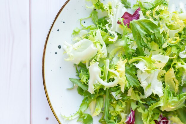 White ceramic plate with fresh salad on wooden surface