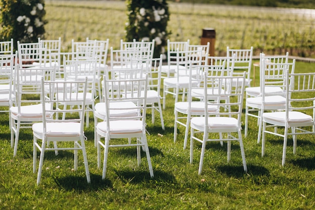 Free photo white chairs on the grass in front of wedding ceremony arch