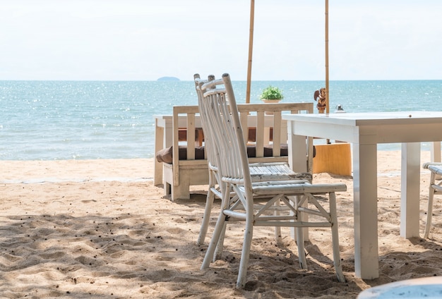 white chairs and table on beach with a view of blue ocean and clear sky