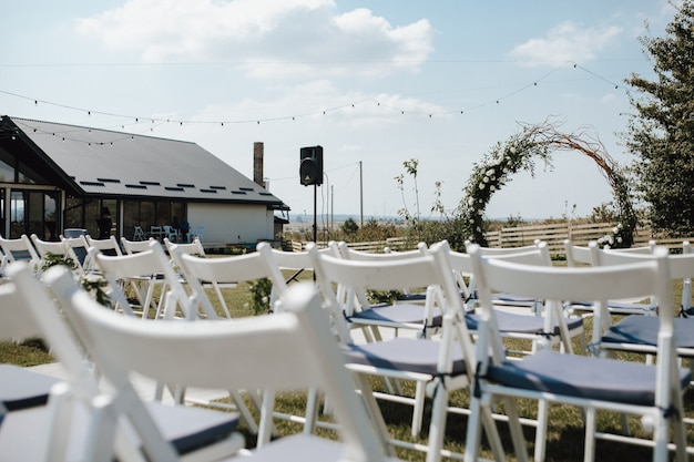 Free photo white chiavari chairs for guests, ceremonial wedding arch on the decorated for the wedding ceremony