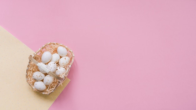 White chicken eggs in basket on pink table