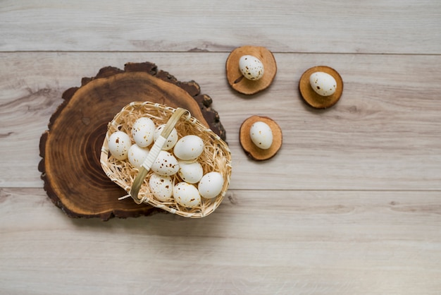 White chicken eggs in basket on wooden board 