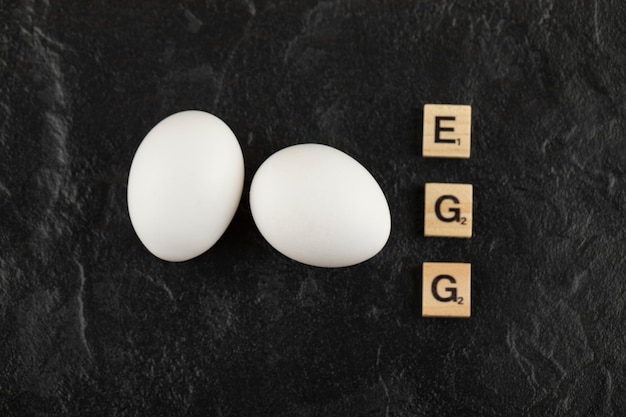 Free photo white chicken eggs on a black table .