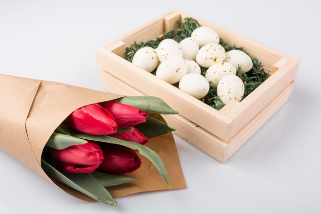 White chicken eggs in box with tulips bouquet 