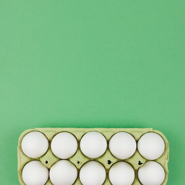 Free photo white chicken eggs in rack on green table