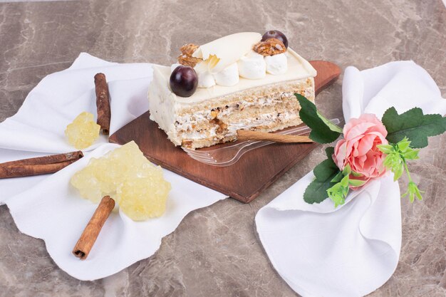 White chocolate cake on wooden board with cloth and candies.