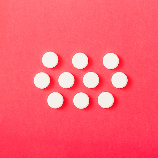 Free Photo white circular pills over the red backdrop