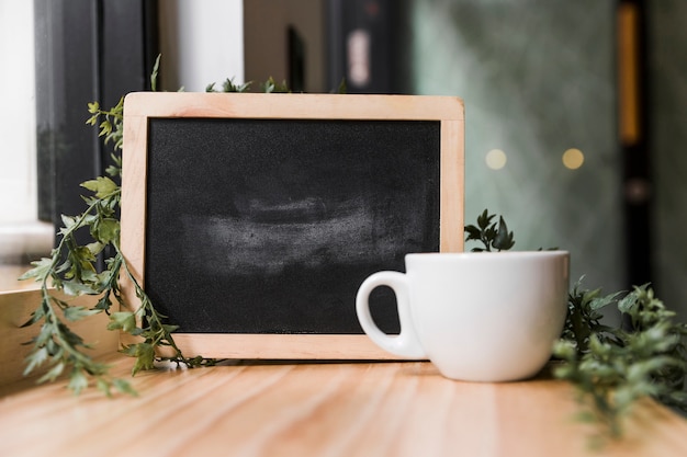 White coffee cup with black slate on wooden surface