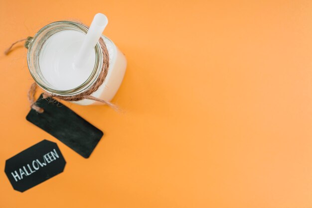 White colour drink in bottle with straw and label near inscription Halloween