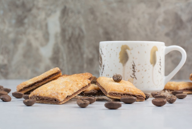 White cup of coffee with crackers and coffee beans on white background. High quality photo