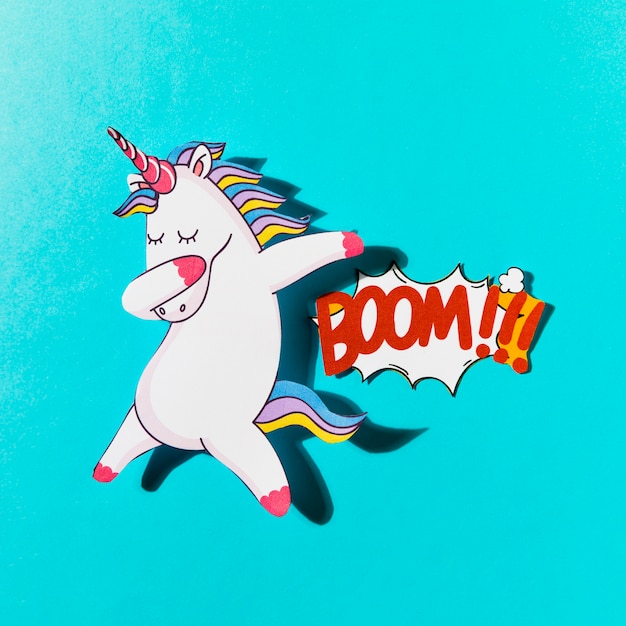 Free Photo white dabbing unicorn with boom comic text on blue backdrop