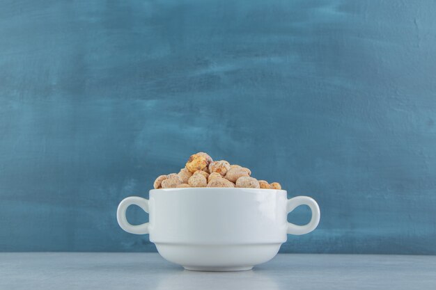 A white deep cup full of delicious dried fruit .