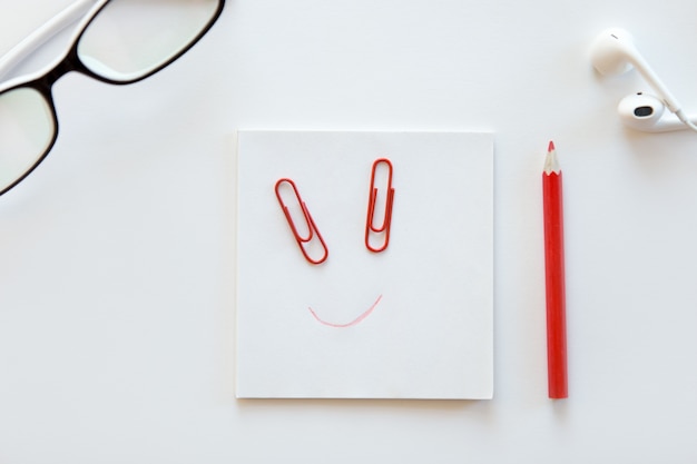 White desk with paper block, a drawn smile on it