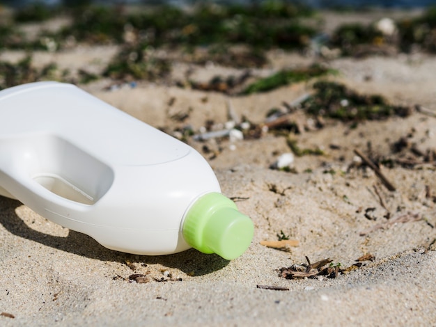 White detergent bottle on beach sand