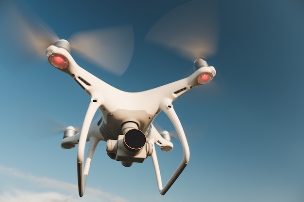 Free Photo white drone hovering in a bright blue sky