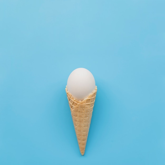 Free photo white egg in waffle horn on blue background