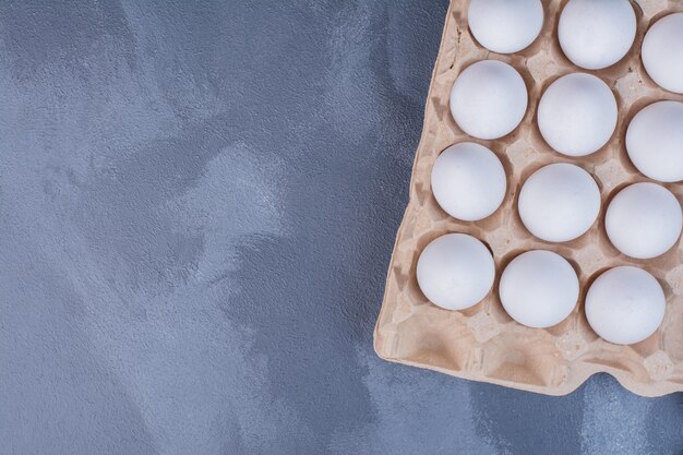 White eggs in a cardboard container.