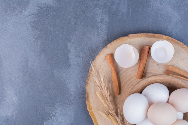 White eggs and eggshells on a wooden platter.