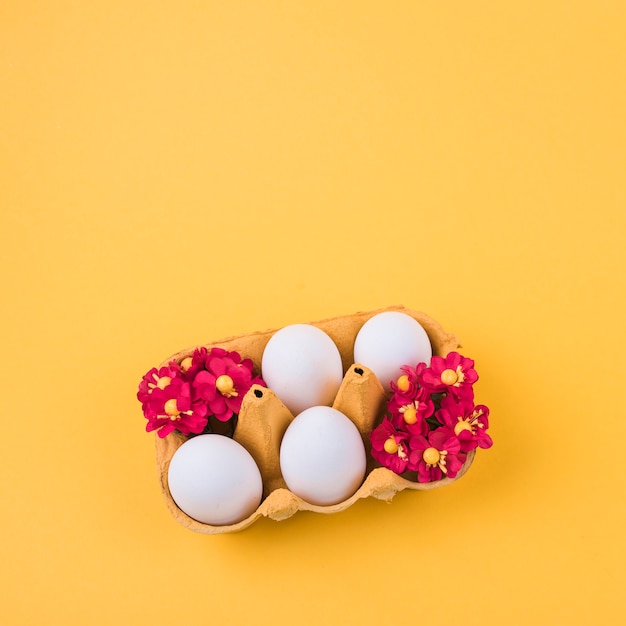 White eggs in rack with flowers on table