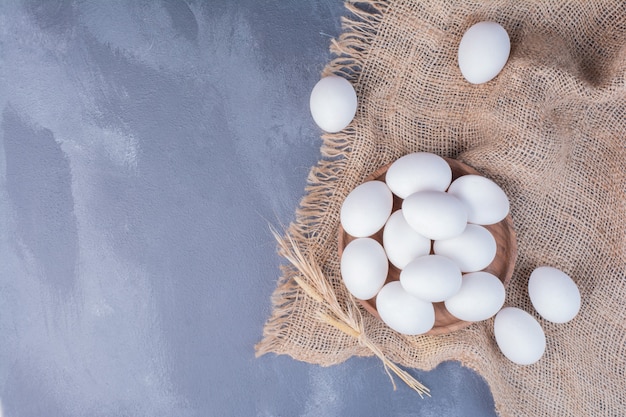 Free photo white eggs in a wooden platter on the burlap