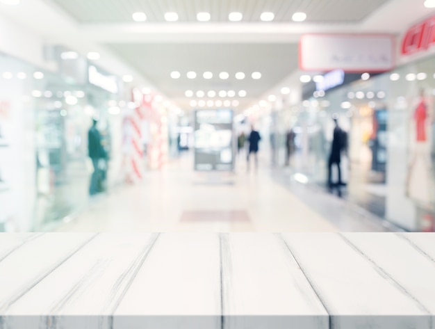 Free photo white empty desk in front of blur illuminated shopping center