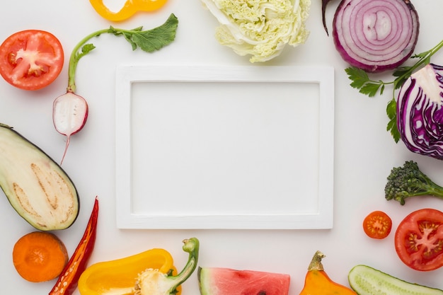 Free photo white empty frame with arrangement of vegetables