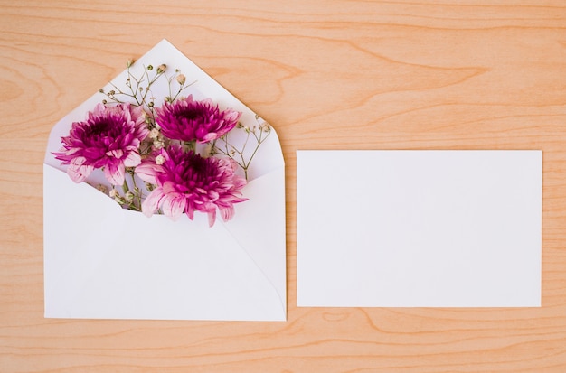 White envelope with flowers and card on wooden textured background