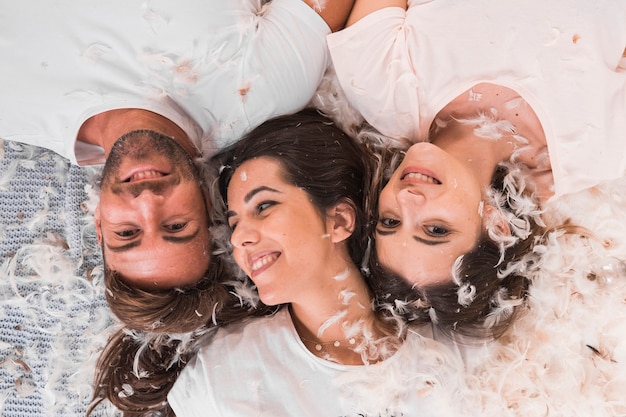 Free photo white feather over the friends lying on bed