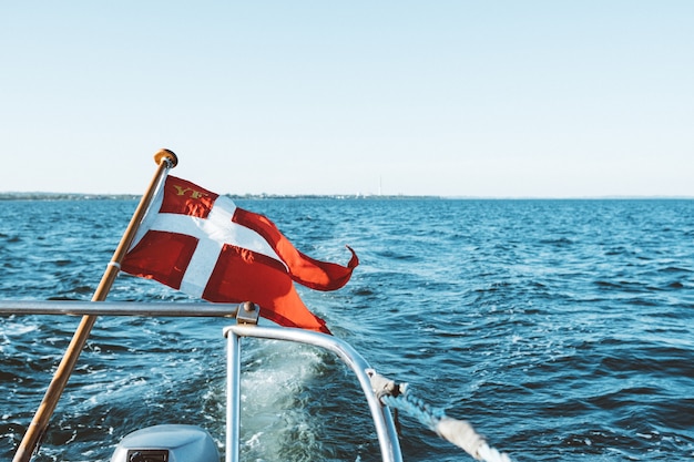 Free photo and white flag on a boat floating on top of the ocean under a blue sky during daytime