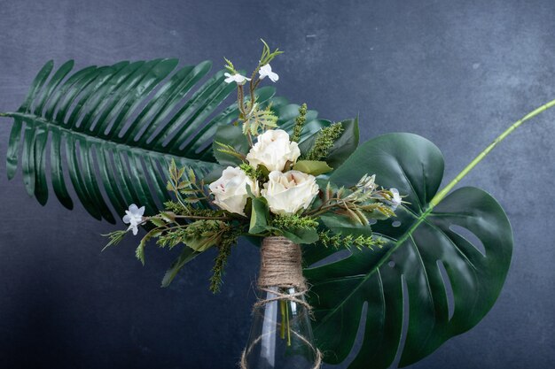 White flowers in ceramic vase on dark wall.