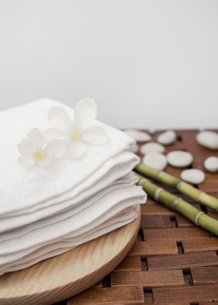 Free photo white flowers and stacked towels on wooden tray