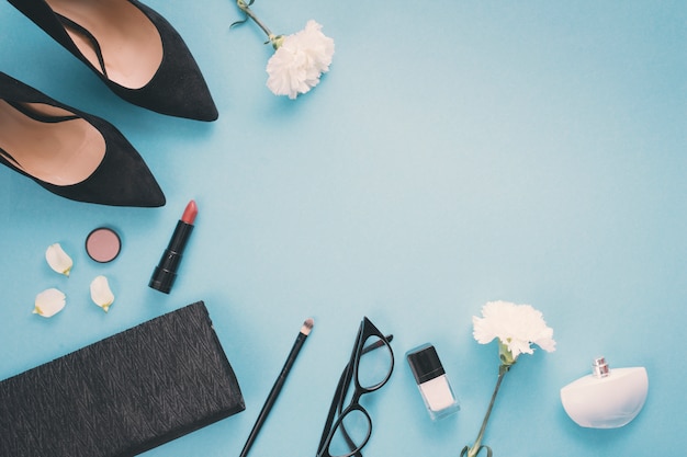 White flowers with cosmetics and woman shoes on table