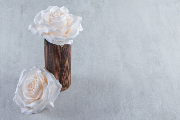 White flowers in a wooden jug, on the white table.