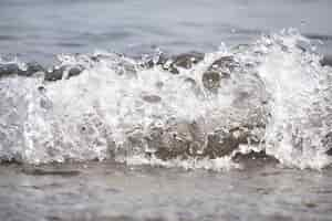 Free photo white foam and sea water drop splashes slow motion with sand and blue water