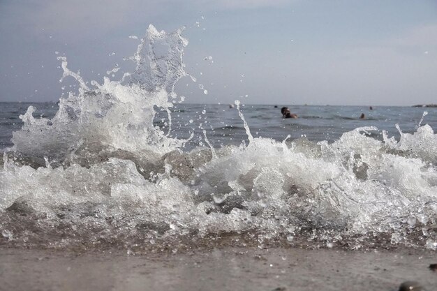 White foam and sea water drop splashes slow motion with sand and blue water