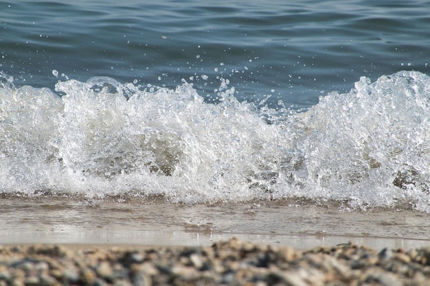 White foam and sea water drop splashes slow motion with sand and blue water