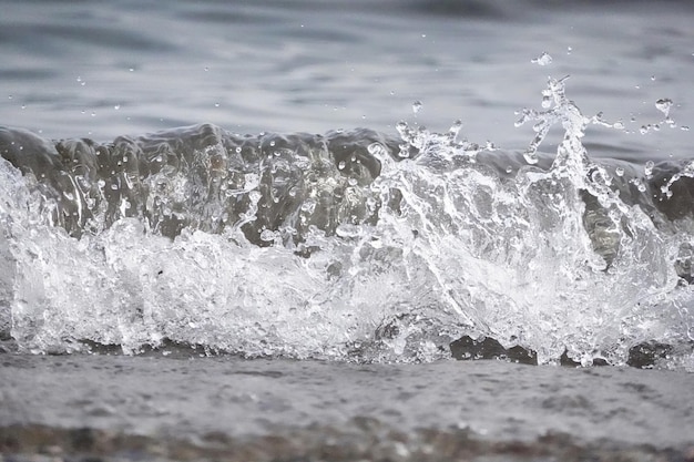 Free photo white foam and sea water drop splashes slow motion with sand and blue water