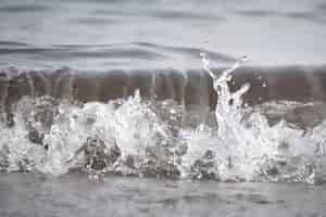 Free photo white foam and sea water drop splashes slow motion with sand and blue water