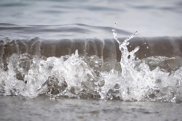 Free Photo white foam and sea water drop splashes slow motion with sand and blue water