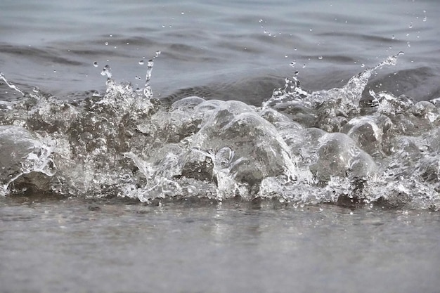 Free photo white foam and sea water drop splashes slow motion with sand and blue water