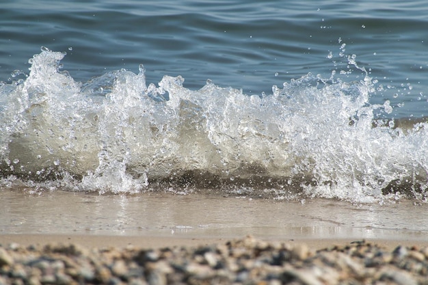 Free photo white foam and sea water drop splashes slow motion with sand and blue water