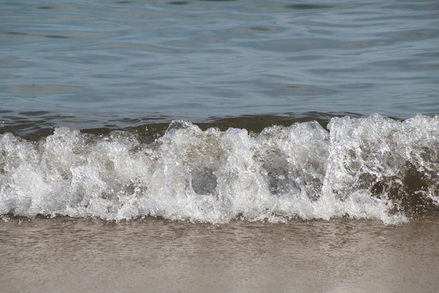 Free photo white foam and sea water drop splashes slow motion with sand and blue water