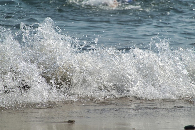 Free photo white foam and sea water drop splashes slow motion with sand and blue water