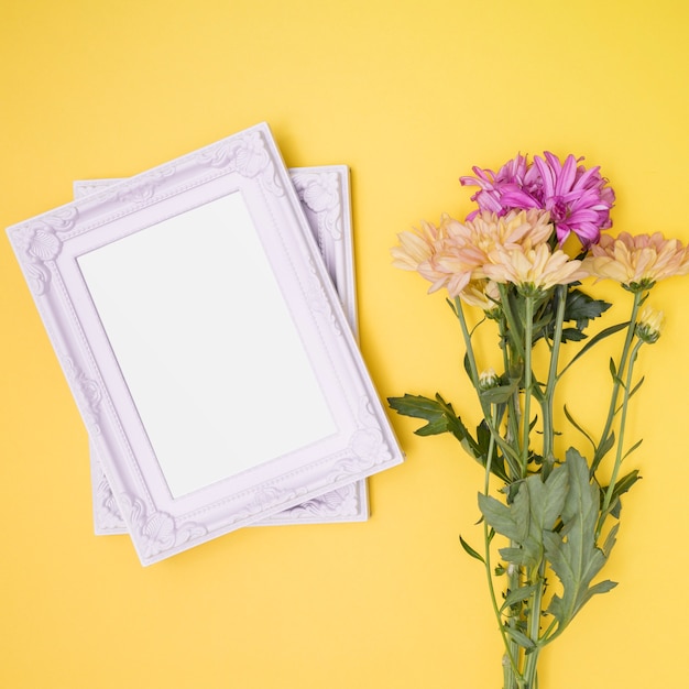 Free photo white frames next to bouquet of flowers