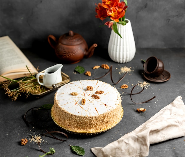 White glazed cake decorated with cake crumbles and walnuts