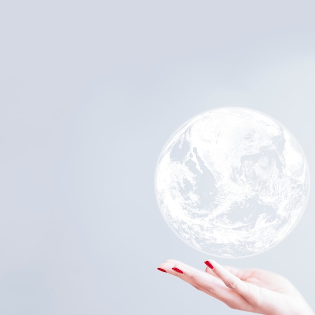 Free photo white globe over woman hand gray background