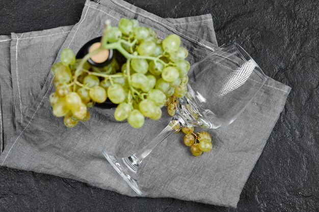 White grapes and a bottle of wine on dark surface