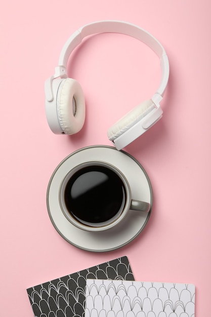 Free photo white headphones with a cup of coffee on a pink background