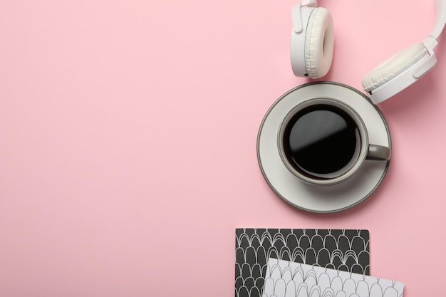 Free photo white headphones with a cup of coffee on a pink background