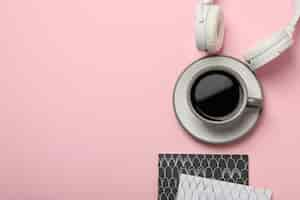 Free photo white headphones with a cup of coffee on a pink background